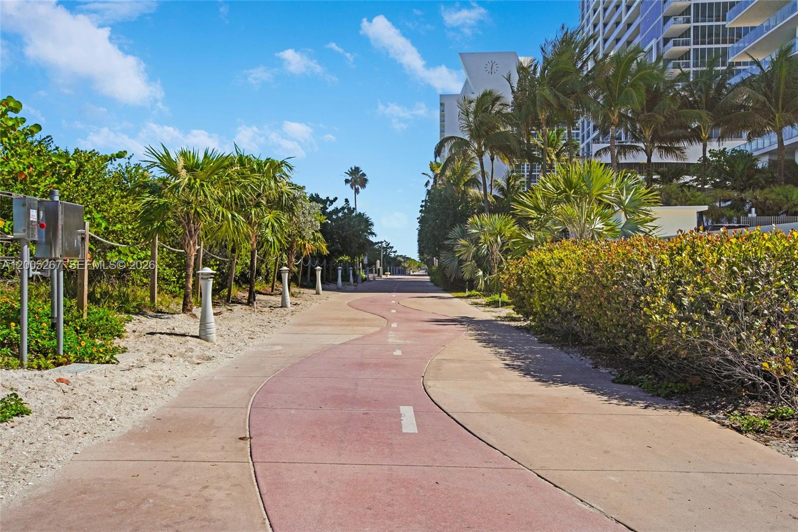 A winding paved path runs between lush tropical landscaping and a modern high-rise building — 6917 Collins Ave # 820, Miami Beach FL 33141, MIAMI BEACH, FL