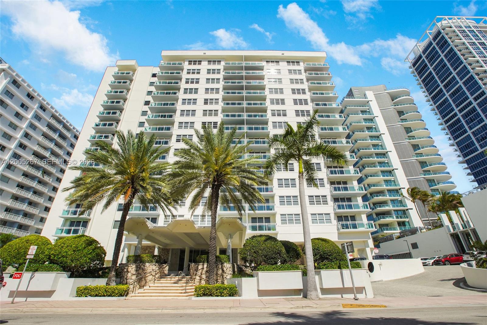 A low-angle exterior view of a multi-story residential building with palm trees and balconies — 6917 Collins Ave # 820, Miami Beach FL 33141, MIAMI BEACH, FL