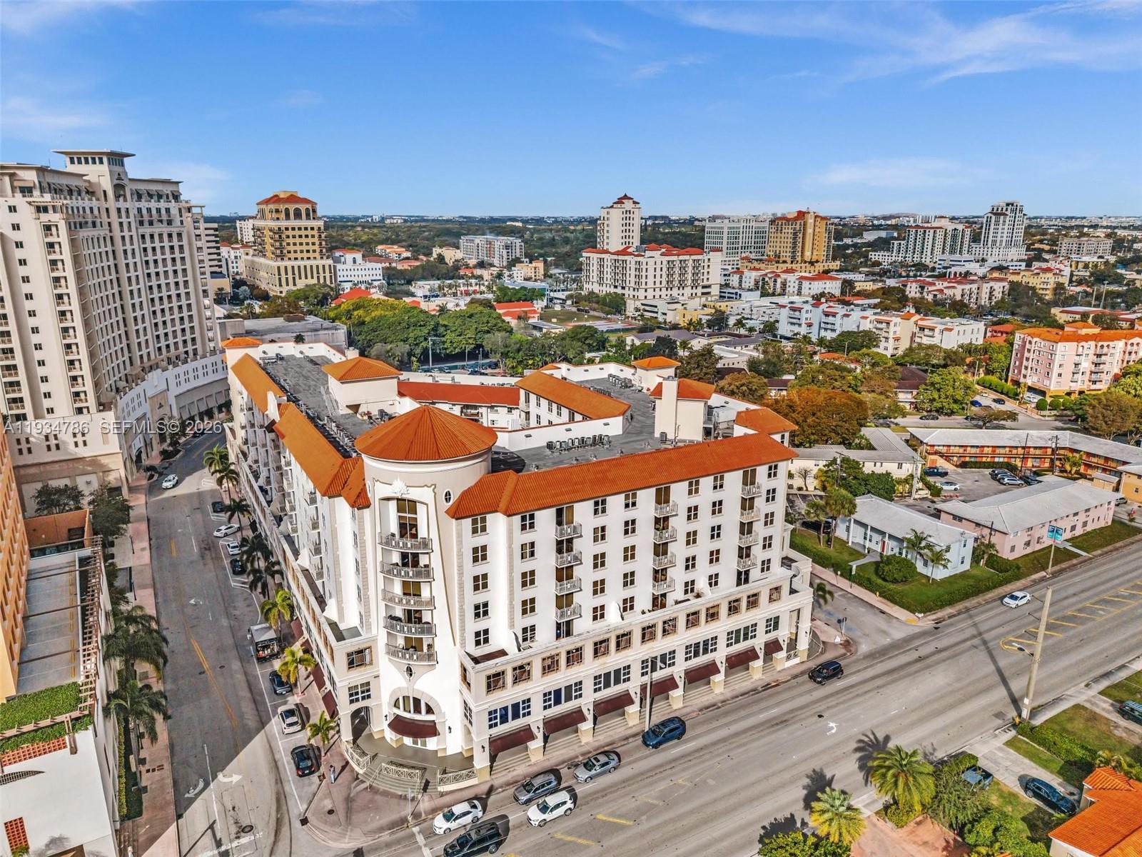 An aerial view shows a multi-story building with a red tile roof and surrounding streets — 2030 S Douglas Rd # 109, Coral Gables FL 33134, CORAL GABLES, FL
