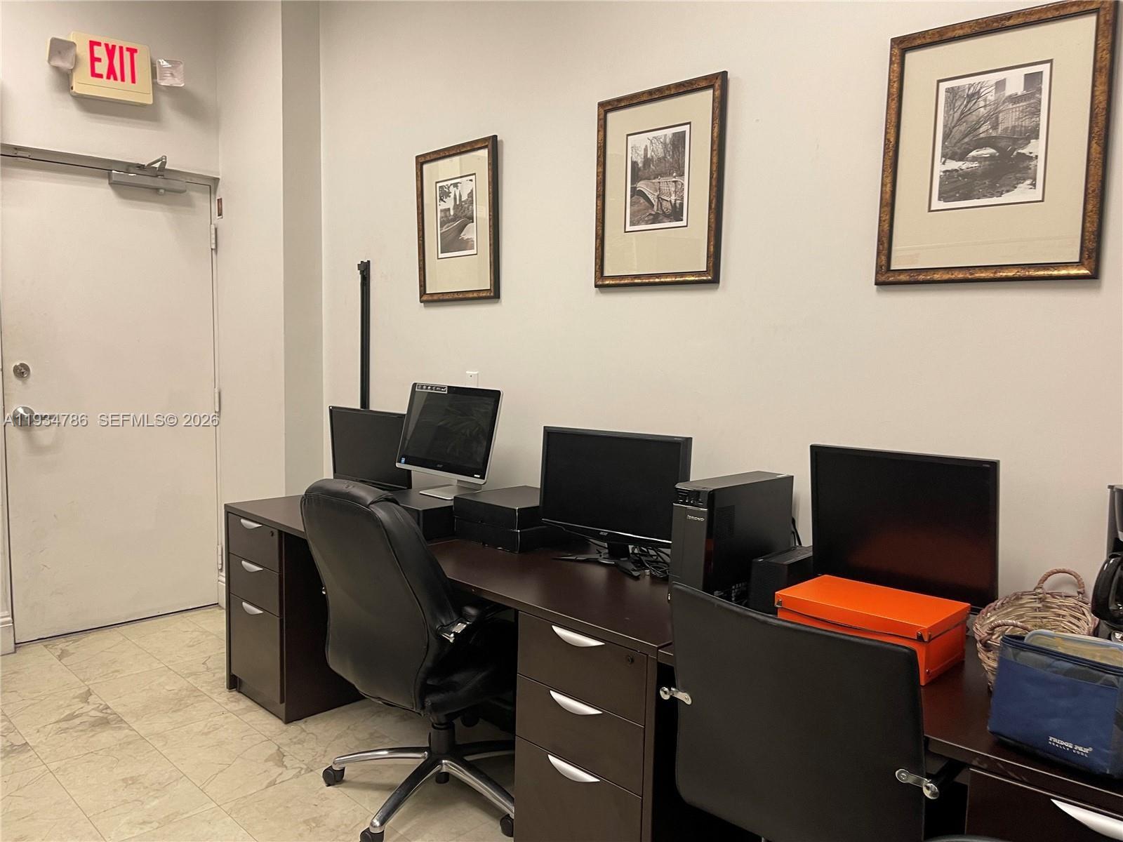 An office space features two dark wood desks with computers, chairs, and framed wall art — 2030 S Douglas Rd # 109, Coral Gables FL 33134, CORAL GABLES, FL