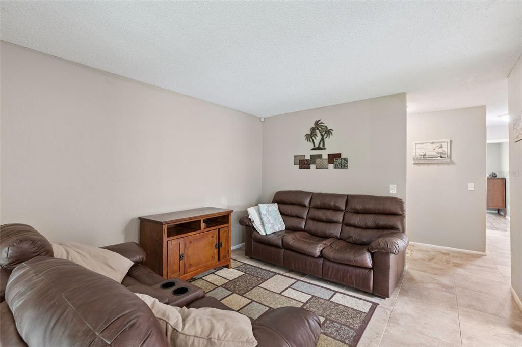 A living room features brown leather sofas, a wooden media console, and a patterned rug — 2417 BARLEY CLUB COURT UNIT 1, ORLANDO, FL