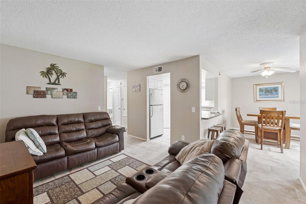 A living room with brown leather sofas, a patterned rug, and an adjacent dining area — 2417 BARLEY CLUB COURT UNIT 1, ORLANDO, FL