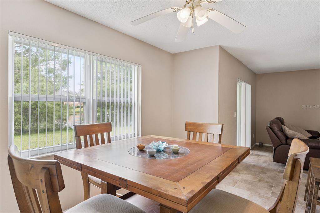 A dining area features a wooden table, chairs, a ceiling fan, and a large window — 2417 BARLEY CLUB COURT UNIT 1, ORLANDO, FL