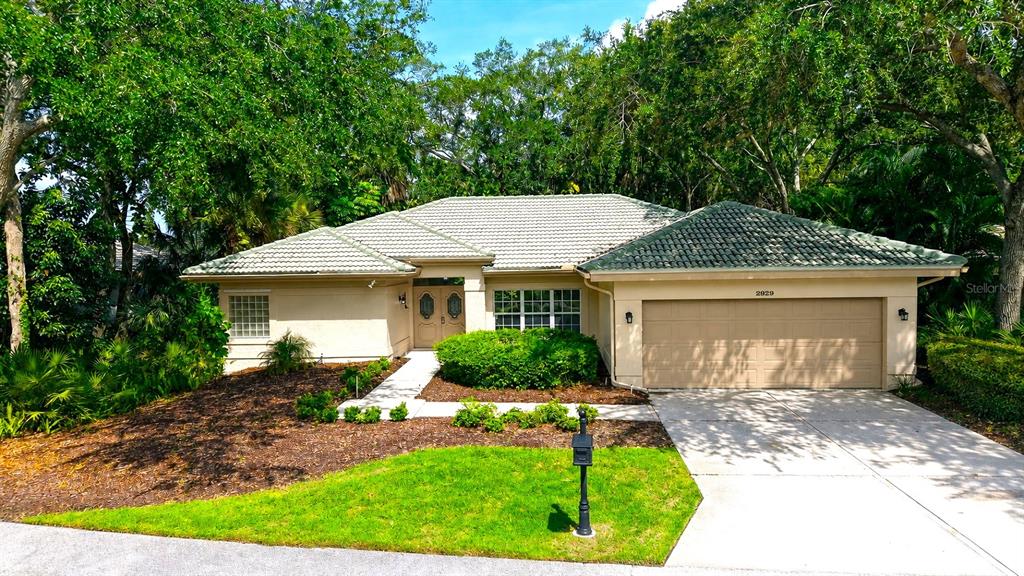 A single-story house with a beige stucco exterior, a tiled roof, and a two-car garage — 2929 SANDRINGHAM PLACE, SARASOTA, FL