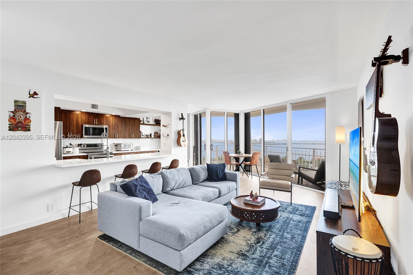 A living room with a sectional sofa, kitchen bar, and balcony overlooking the water — 2000 Towerside Ter, Miami FL 33138, MIAMI, FL
