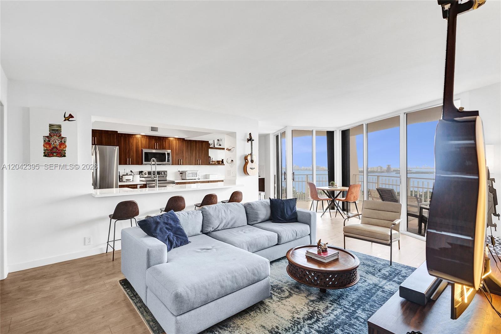 A living room with a sectional sofa, kitchen pass-through, and floor-to-ceiling windows overlooking water — 2000 Towerside Ter, Miami FL 33138, MIAMI, FL