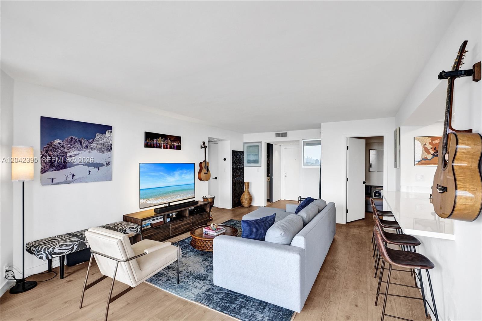 A living room features a sofa, television, and two guitars mounted on the walls — 2000 Towerside Ter, Miami FL 33138, MIAMI, FL