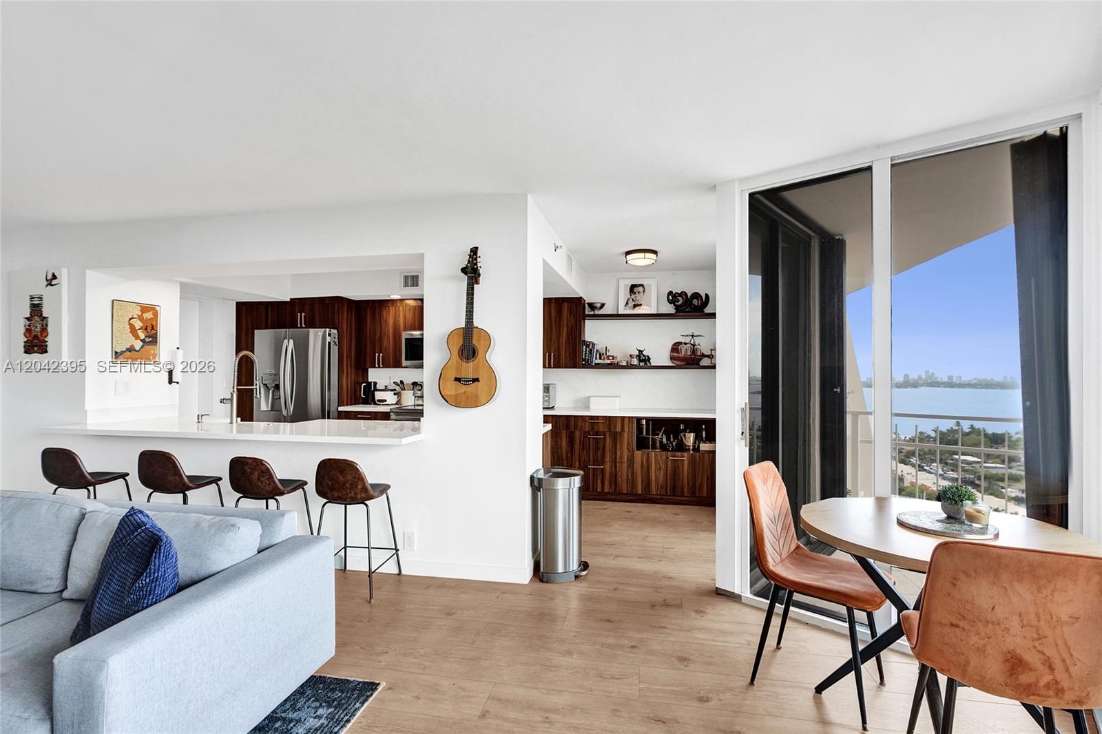 An open-concept living area features a kitchen with wood cabinets, bar seating, and balcony views — 2000 Towerside Ter, Miami FL 33138, MIAMI, FL