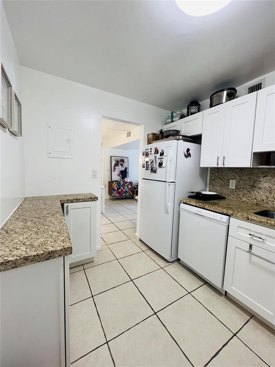 A kitchen features white cabinets, granite countertops, tile flooring, and a white refrigerator — 4040 N Hills Drive # 7, Hollywood FL 33021, HOLLYWOOD, FL