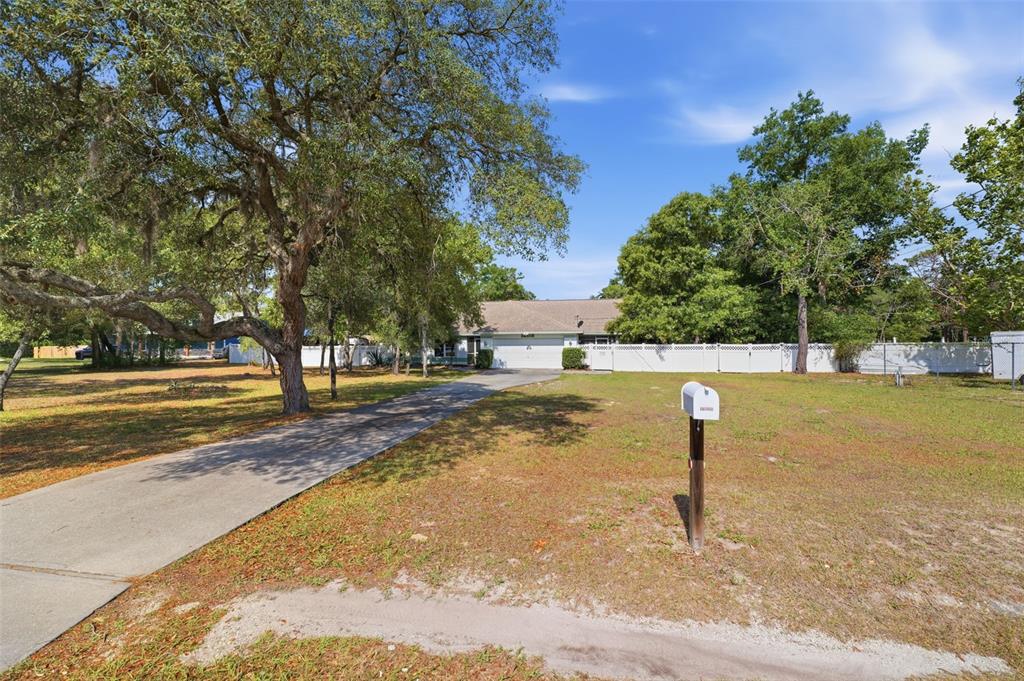 A single-story house with a white stucco facade, green trim, and a two-car garage — 12515 CANTON AVENUE, HUDSON, FL