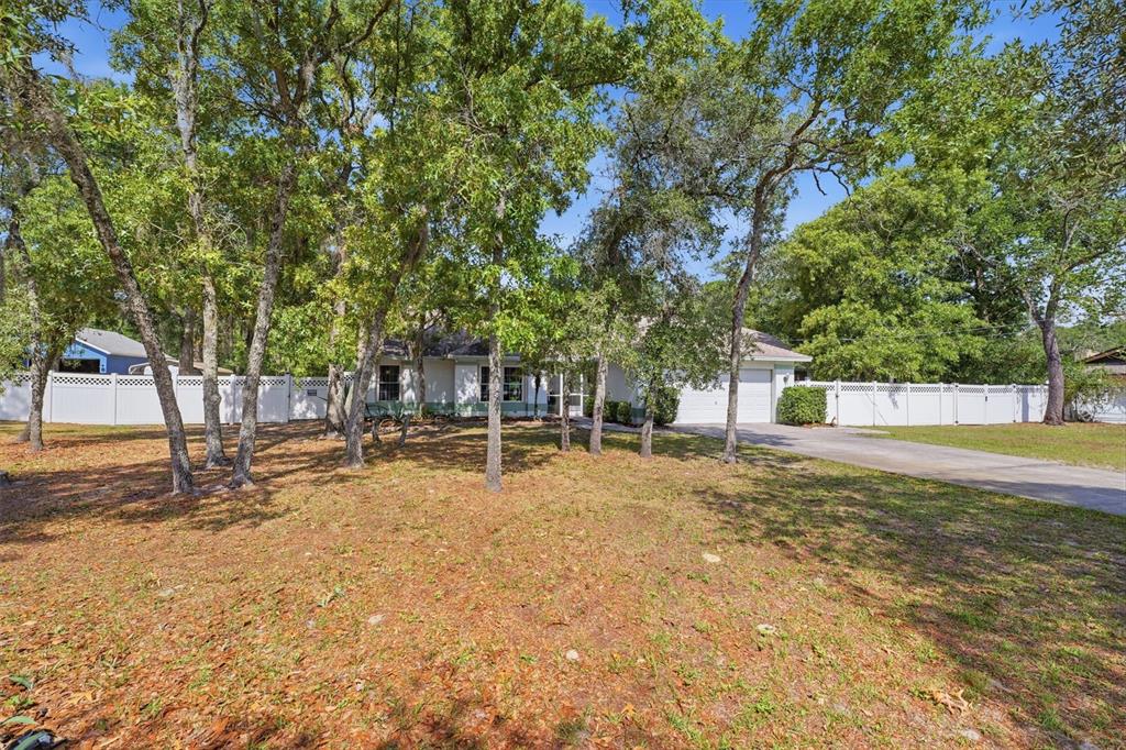 An aerial view shows a residential property with a house, detached garage, and surrounding trees — 12515 CANTON AVENUE, HUDSON, FL