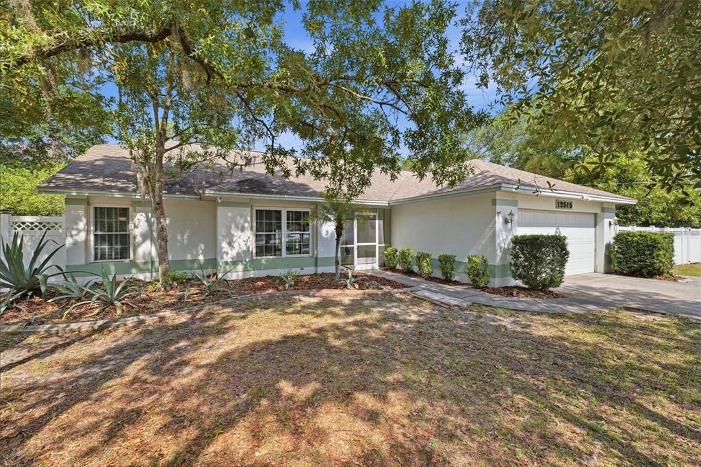 A metal carport and attached storage shed sit on a concrete slab in a wooded yard — 12515 CANTON AVENUE, HUDSON, FL