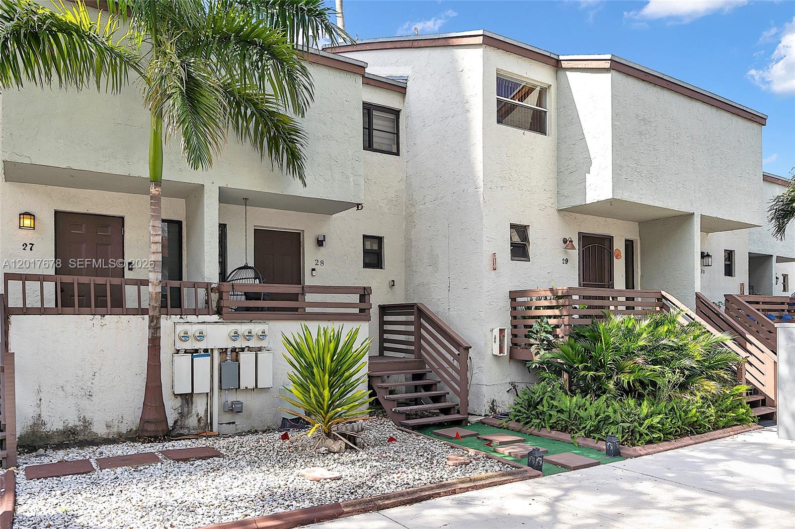 A row of multi-story townhouses with brown wooden railings, stairs, and gravel landscaping — 1901 NW S River Dr # 28C, Miami FL 33125, MIAMI, FL