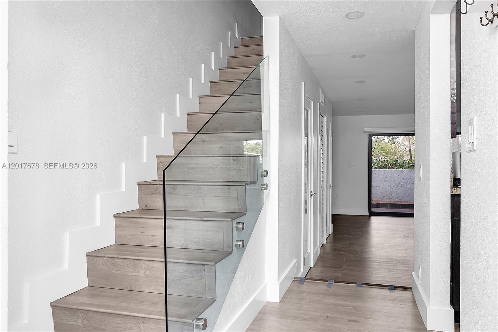 A staircase with light wood treads and a glass railing leads to an upper floor — 1901 NW S River Dr # 28C, Miami FL 33125, MIAMI, FL