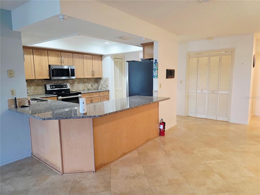 A kitchen with light wood cabinets, granite countertops, and a breakfast bar island — 1924 NEW BEDFORD DRIVE, SUN CITY CENTER, FL