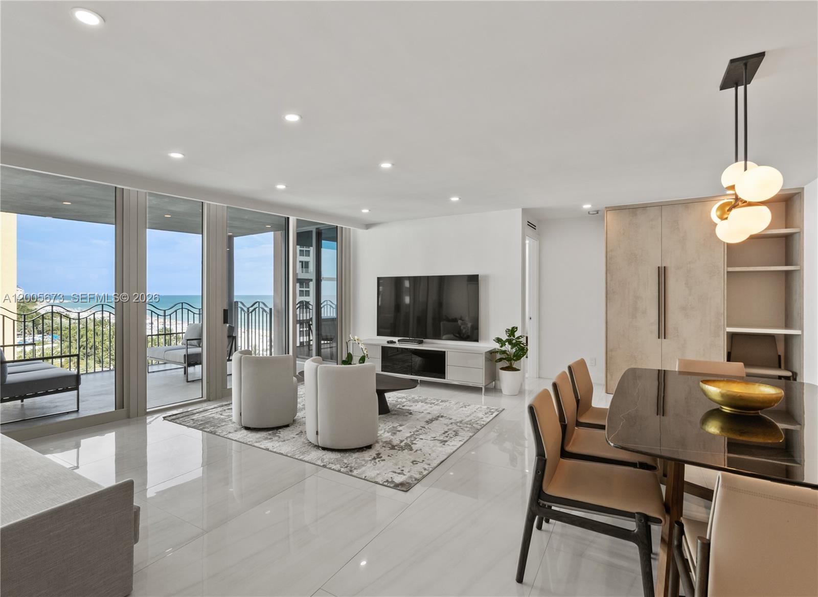 A modern living and dining area features white tile floors, floor-to-ceiling windows, and ocean views — 1500 Ocean Dr # 1003, Miami Beach FL 33139, MIAMI BEACH, FL