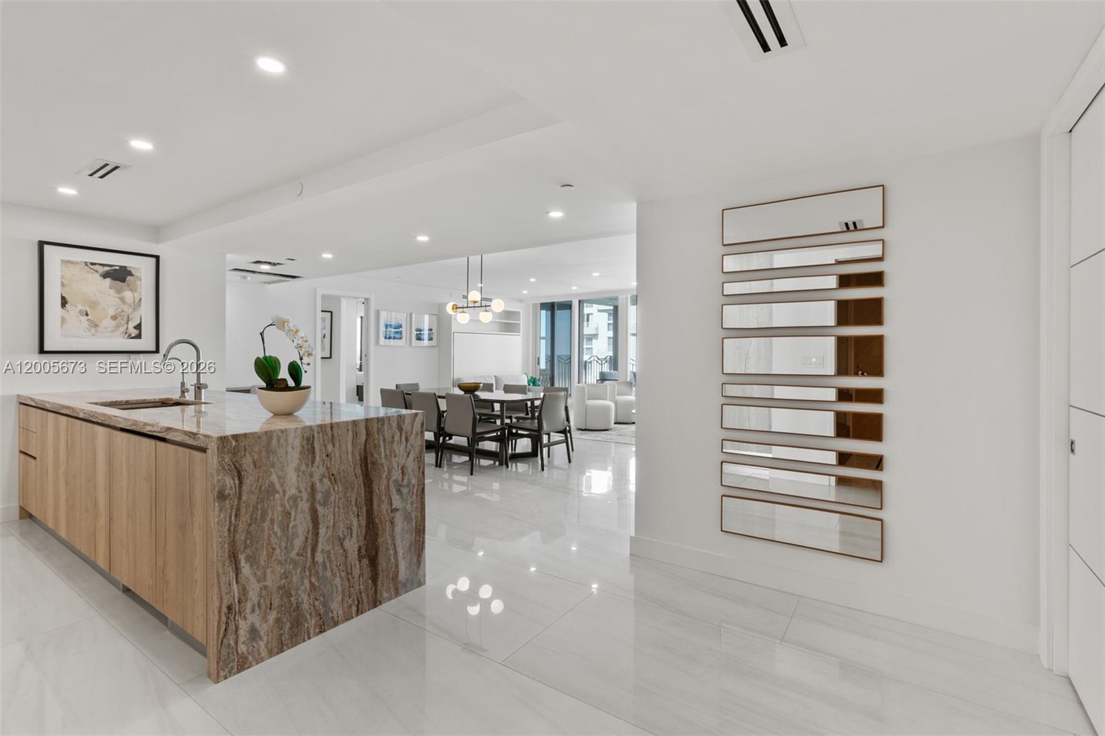 A kitchen with a marble island and dining area features white floors and modern decor — 1500 Ocean Dr # 1003, Miami Beach FL 33139, MIAMI BEACH, FL