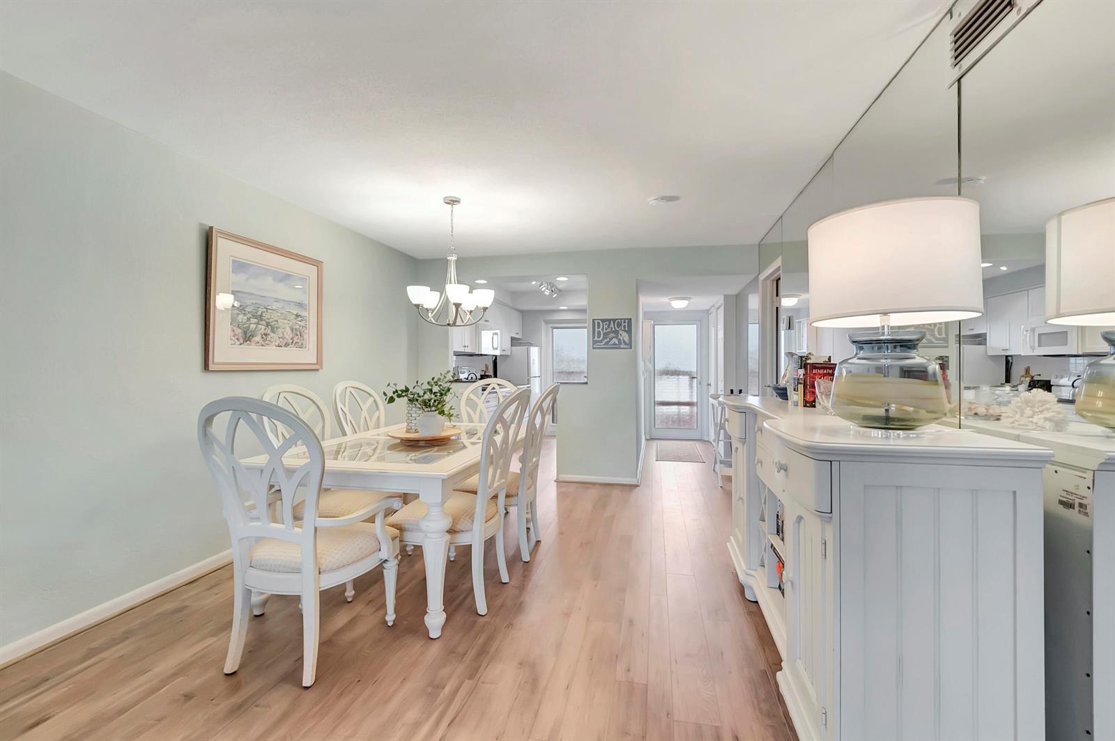 A dining room features a white table and chairs, light wood flooring, and mirrored walls — 1910 S Ocean Boulevard # 416, Delray Beach FL 33483, DELRAY BEACH, FL