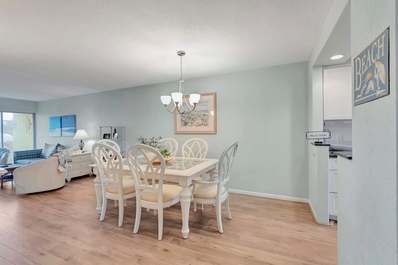 A dining area with a white table and chairs sits adjacent to a living room — 1910 S Ocean Boulevard # 416, Delray Beach FL 33483, DELRAY BEACH, FL