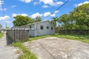 A view of the side of a light-colored house with a concrete driveway and fence — 303 NW 7th St # 2, Hallandale Beach FL 33009, HALLANDALE BEACH, FL