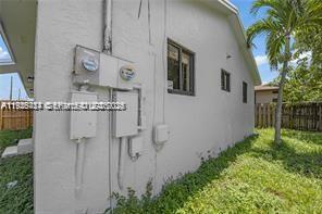 The exterior side of a white stucco house features electrical meters and utility boxes — 303 NW 7th St # 2, Hallandale Beach FL 33009, HALLANDALE BEACH, FL