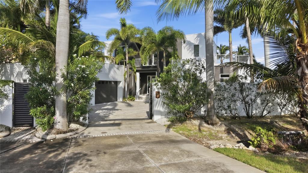 A modern two-story house with a paved driveway, palm trees, and a dark garage door — 1475 JOHN RINGLING PARKWAY, SARASOTA, FL