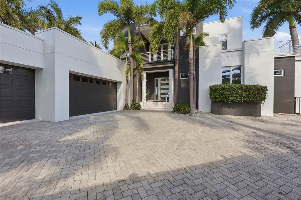 A modern two-story house with a paved driveway, palm trees, and a dark garage door — 1475 JOHN RINGLING PARKWAY, SARASOTA, FL