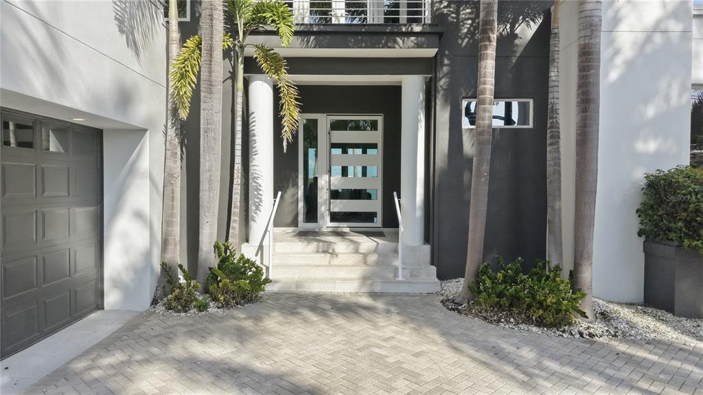 The exterior of a modern home features a paved driveway, palm trees, and a front entrance — 1475 JOHN RINGLING PARKWAY, SARASOTA, FL