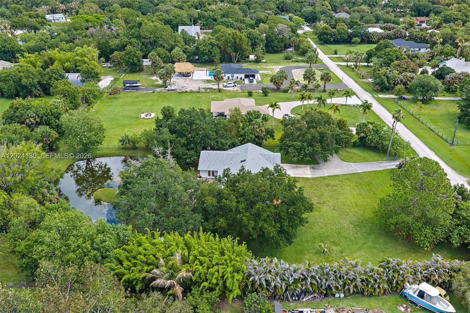 An aerial view shows a house with a pond, large trees, and a boat — 15305 N 96th St N, Palm Beach FL 33478, PALM BEACH, FL
