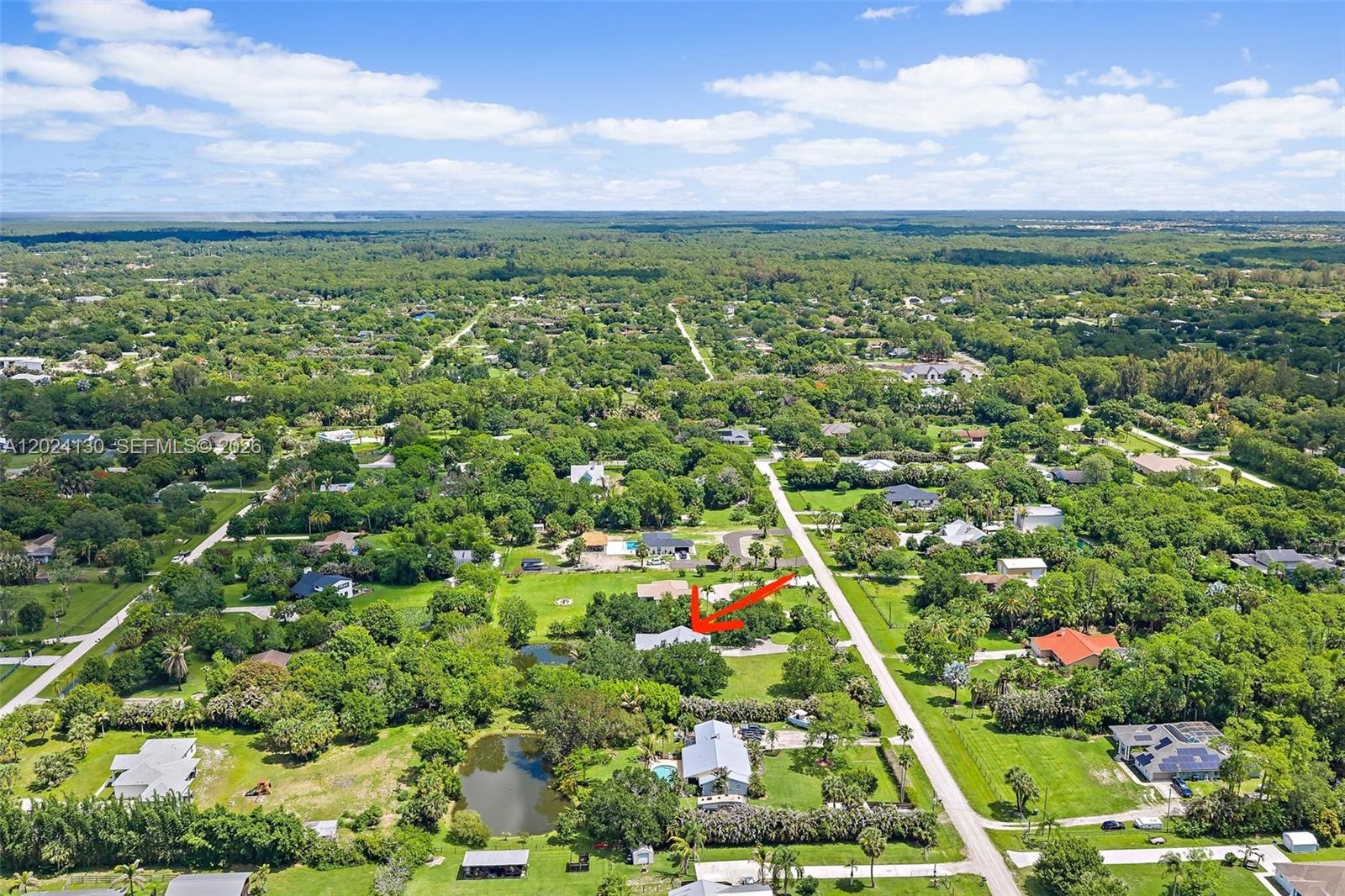 An aerial view shows a residential property with a house, pond, and surrounding greenery — 15305 N 96th St N, Palm Beach FL 33478, PALM BEACH, FL