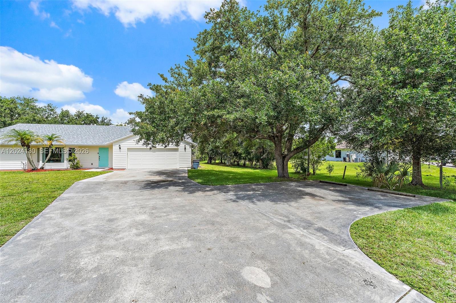 A single-story house with a white exterior, a turquoise front door, and a concrete driveway — 15305 N 96th St N, Palm Beach FL 33478, PALM BEACH, FL