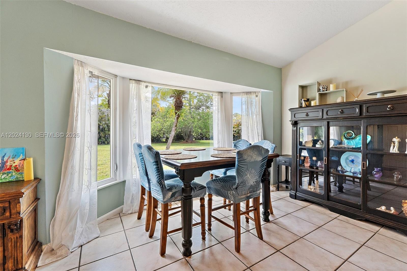 A dining area features a dark wood table, blue patterned chairs, and a large display cabinet — 15305 N 96th St N, Palm Beach FL 33478, PALM BEACH, FL