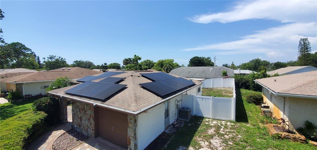An aerial view shows a house roof with solar panels and a white vinyl fence — 7438 LAKE FOREST CIRCLE, PORT RICHEY, FL
