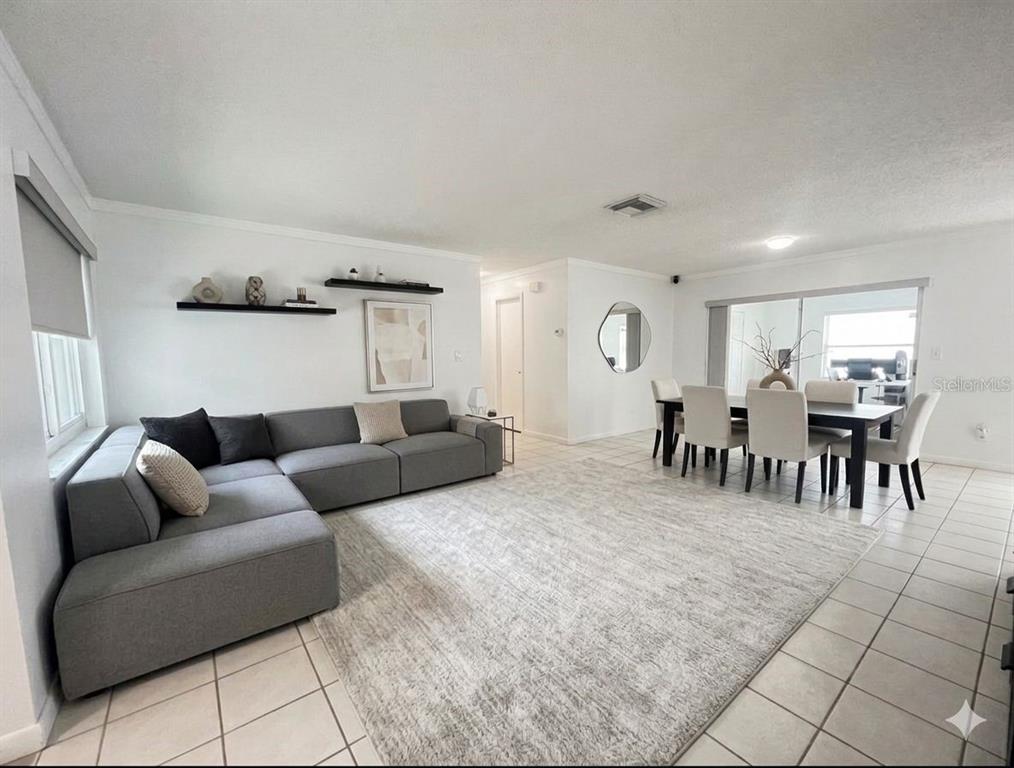 A living and dining area with a grey sectional sofa, dining table, and tiled floors — 7438 LAKE FOREST CIRCLE, PORT RICHEY, FL