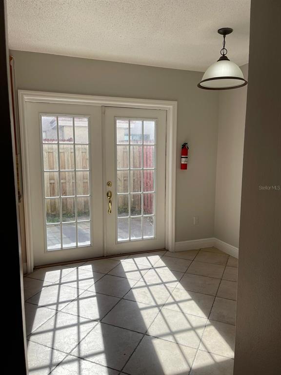 A sunlit room with tiled floors and French doors leading to a fenced outdoor patio — 6218 YORKTOWN DRIVE UNIT 15, ORLANDO, FL