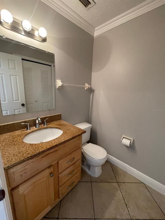 A bathroom features a granite vanity, wooden cabinets, a toilet, and a wall-mounted mirror — 6218 YORKTOWN DRIVE UNIT 15, ORLANDO, FL