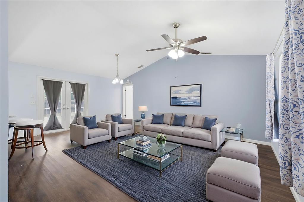 A living room features a vaulted ceiling, light blue walls, a sofa, and armchairs — 8178 ENGLISH ELM CIRCLE, SPRING HILL, FL