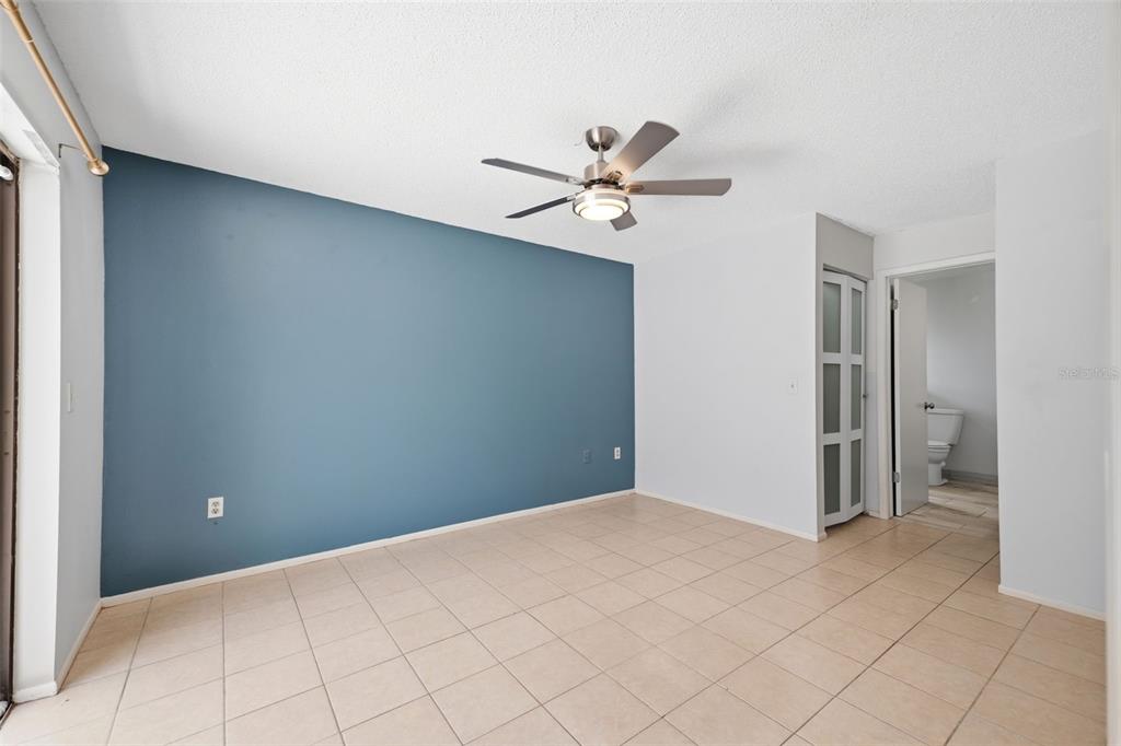 A room with light tile flooring, a blue accent wall, and a ceiling fan — 8178 ENGLISH ELM CIRCLE, SPRING HILL, FL