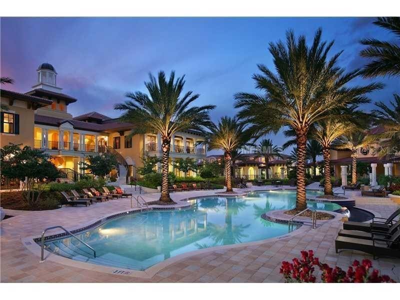 A swimming pool sits in front of a multi-story building surrounded by palm trees — 91 VIVANTE BOULEVARD UNIT 9133, PUNTA GORDA, FL