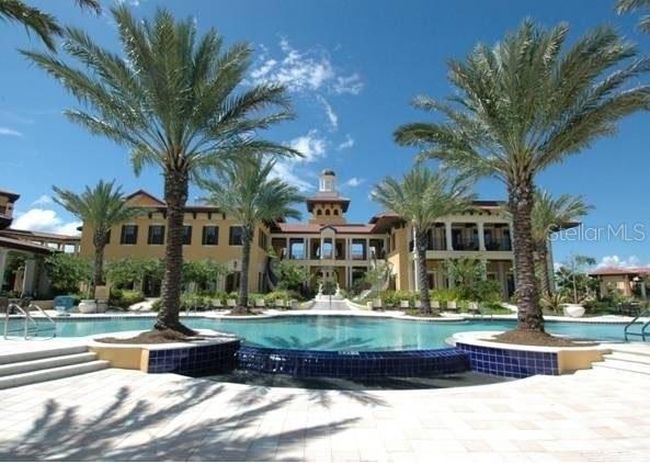 A large swimming pool sits in front of a multi-story building with palm trees — 91 VIVANTE BOULEVARD UNIT 9133, PUNTA GORDA, FL
