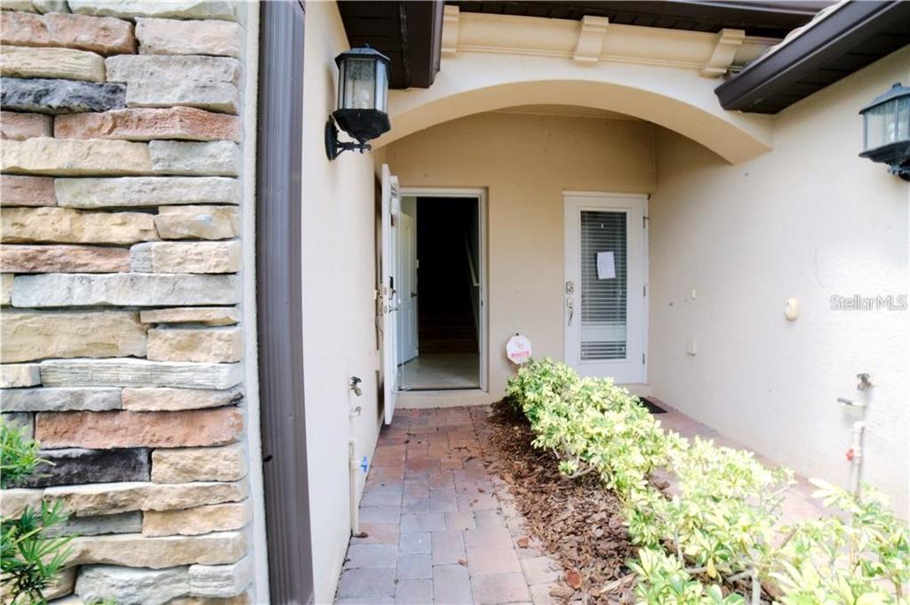 An exterior entryway features a stone-accented wall, a paved walkway, and two doors — 1251 LONG COVE LOOP UNIT 1251, DAVENPORT, FL