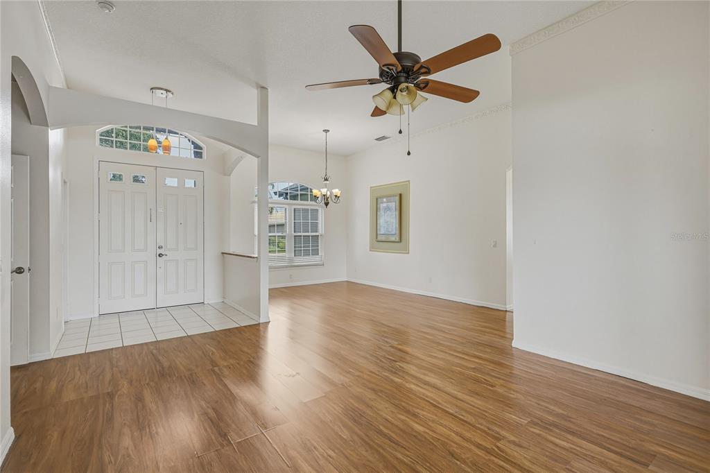 A bright, open-concept living area features wood-look flooring, a ceiling fan, and a front entryway — 6305 ROCK CREEK CIRCLE, ELLENTON, FL