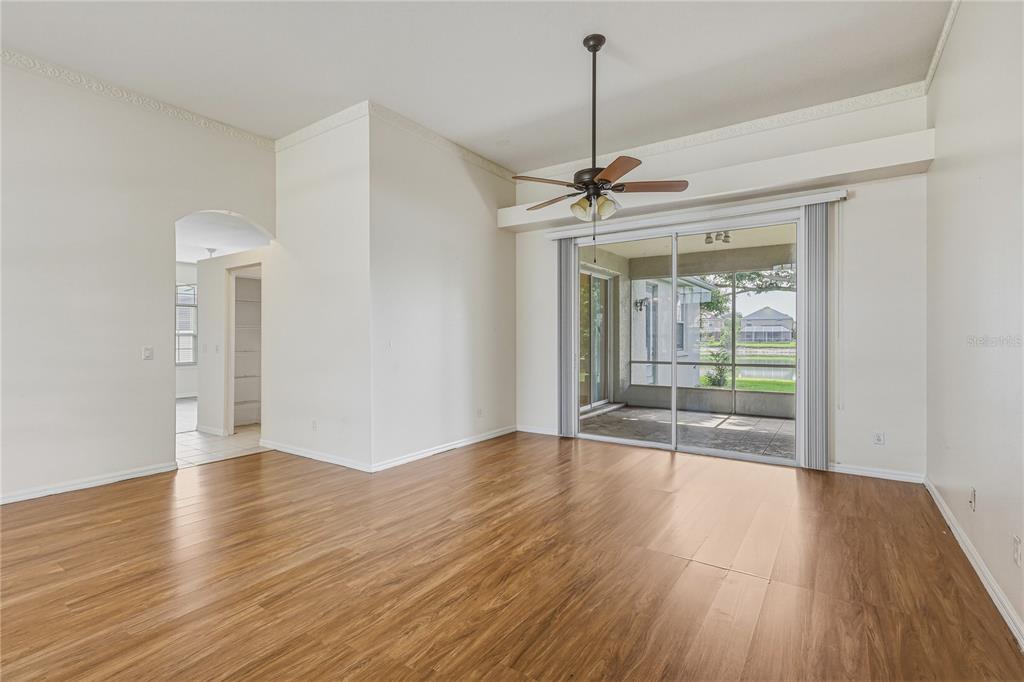 An empty living room features wood-look flooring, a ceiling fan, and sliding glass doors — 6305 ROCK CREEK CIRCLE, ELLENTON, FL
