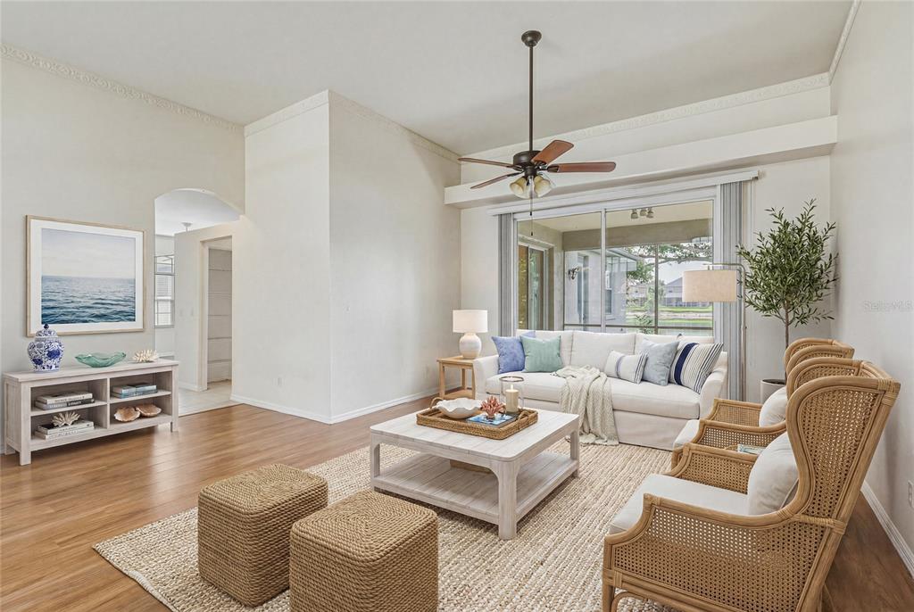 A bright living room features a white sofa, rattan chairs, and a wooden coffee table — 6305 ROCK CREEK CIRCLE, ELLENTON, FL