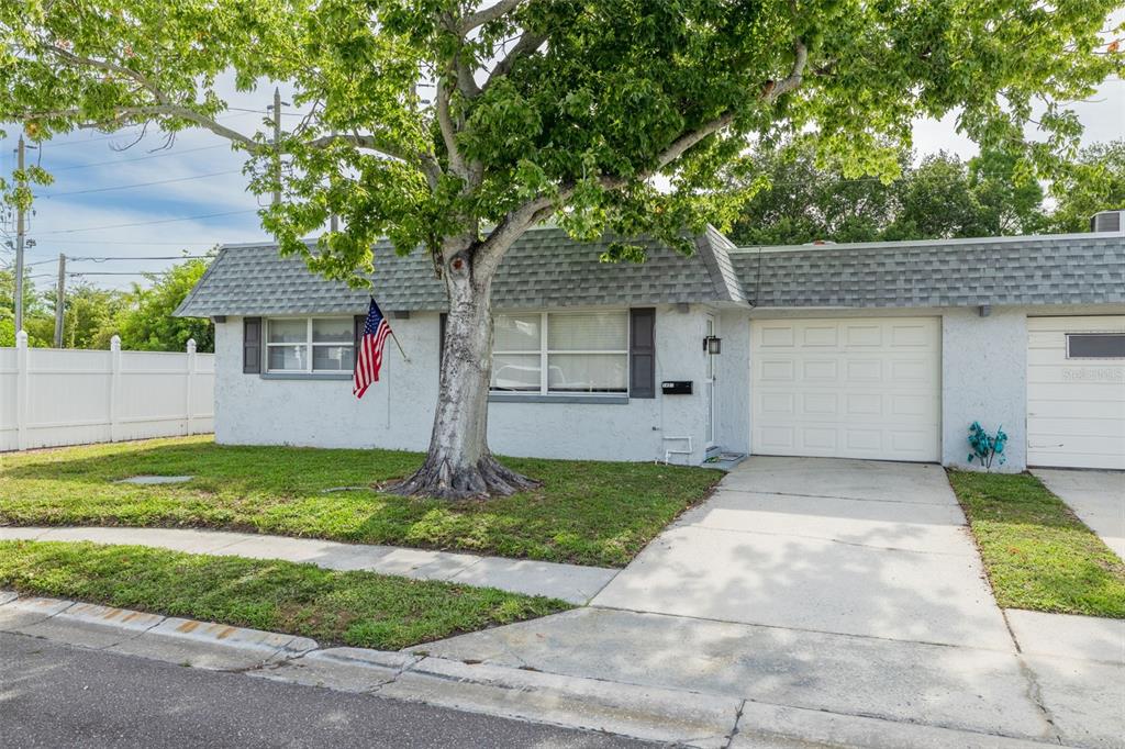 A single-story house with a white stucco exterior, a gray shingled roof, and a driveway — 1401 CARA DRIVE UNIT 1401, LARGO, FL