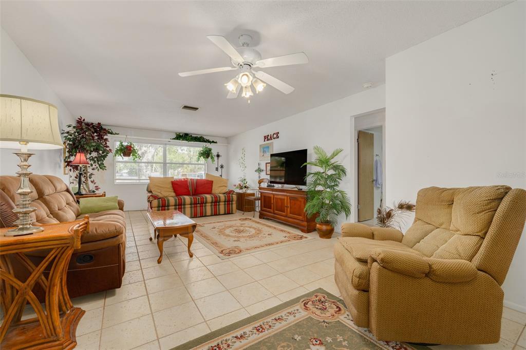 A living room features tile flooring, a ceiling fan, two sofas, and a television console — 1401 CARA DRIVE UNIT 1401, LARGO, FL