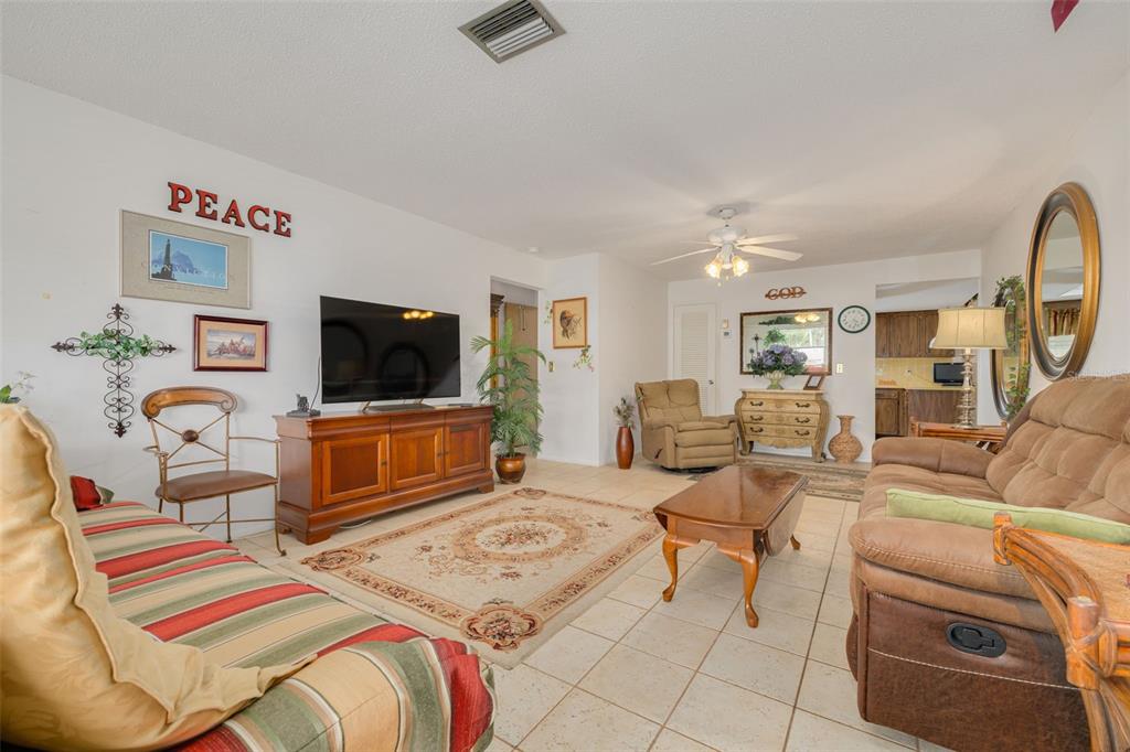 A living room features tile flooring, a television console, and two brown sofas — 1401 CARA DRIVE UNIT 1401, LARGO, FL