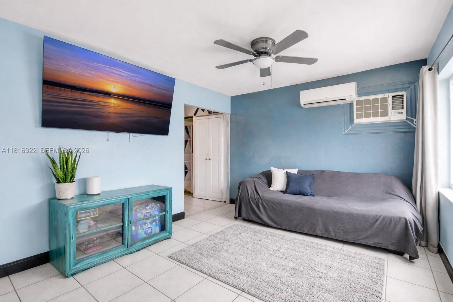 A living room features light blue walls, a gray sofa, a television, and tile flooring — 6336 SW 22nd St, Miramar FL 33023, MIRAMAR, FL