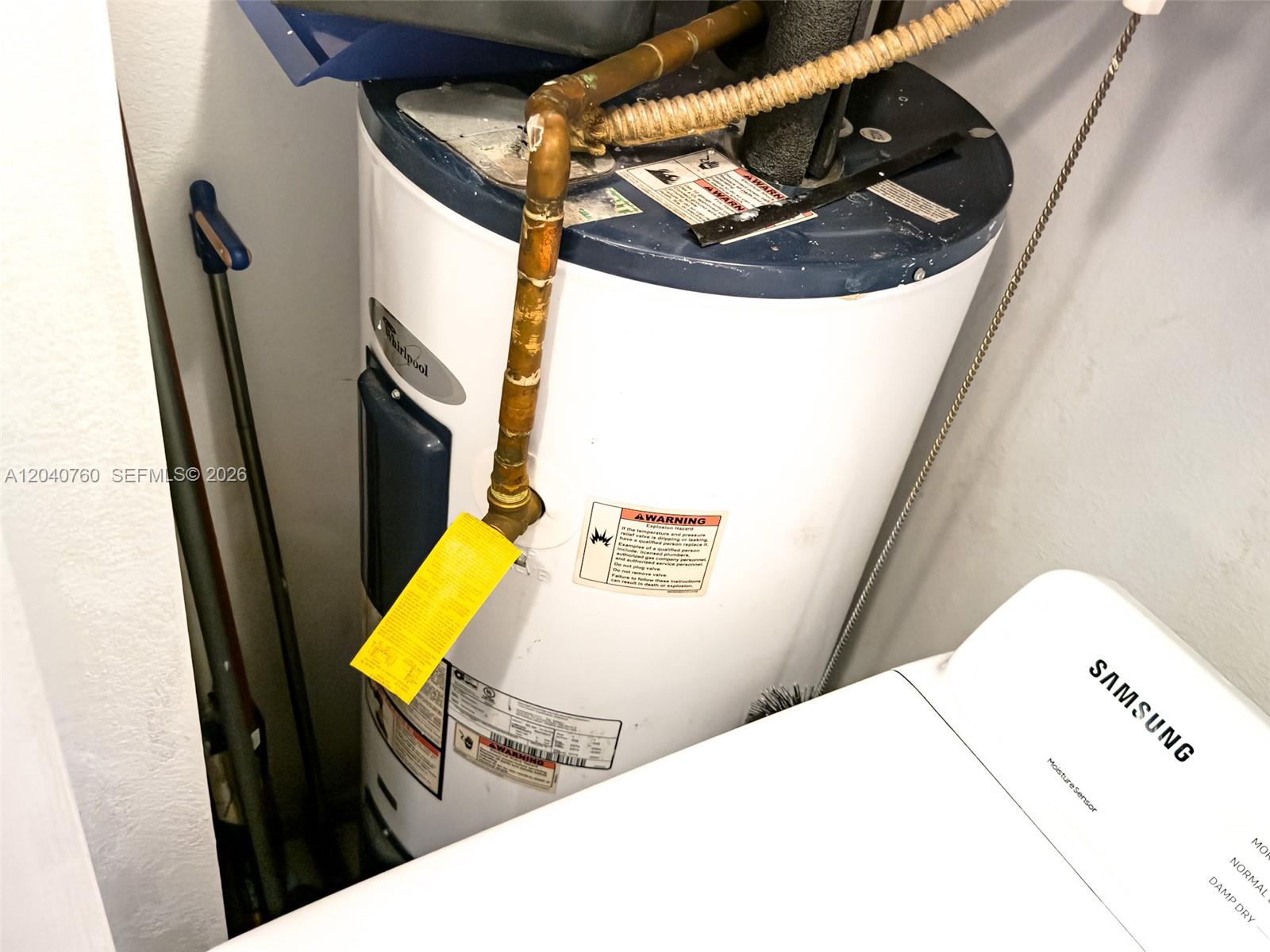 A white Whirlpool water heater stands in a utility closet next to a Samsung dryer — 19251 NW 33rd Ave, Miami Gardens FL 33056, MIAMI GARDENS, FL