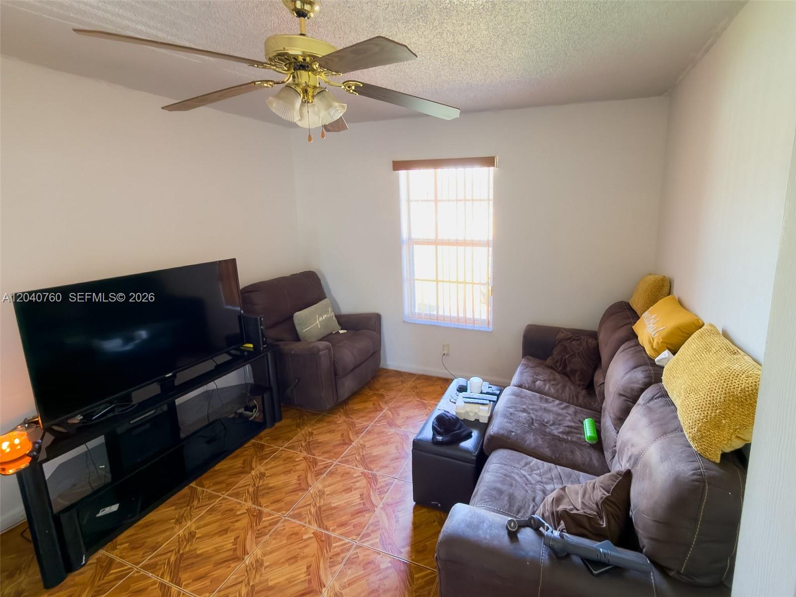 A living room features brown furniture, a television on a stand, and tiled flooring — 19251 NW 33rd Ave, Miami Gardens FL 33056, MIAMI GARDENS, FL